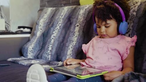 Child Using Tablet with Headphones on Couch