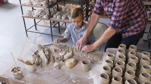 Boy and Man Shaping Clay in Pottery Studio