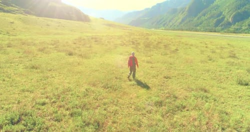 Flight Over Backpack Hiking Tourist Walking Across Green Mountain Field