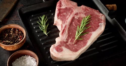 Rohes Steak Beef T-Bone in einer Bratpfanne dreht sich langsam.