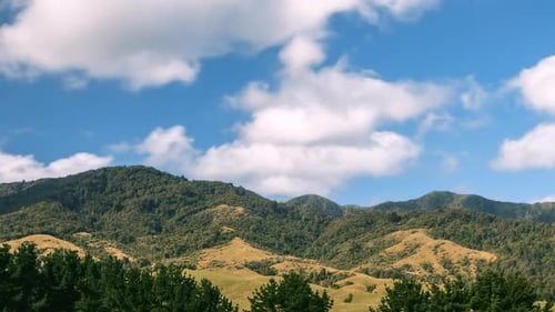 Rolling Green Hills and Mountains Under Blue Sky