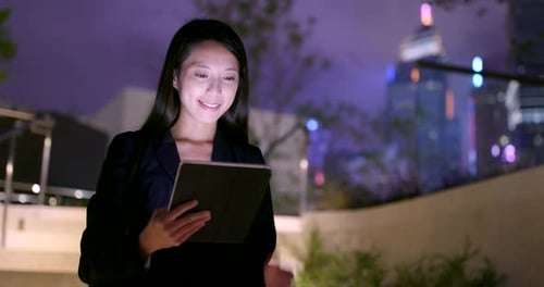 Young Woman Using Tablet at Night in City