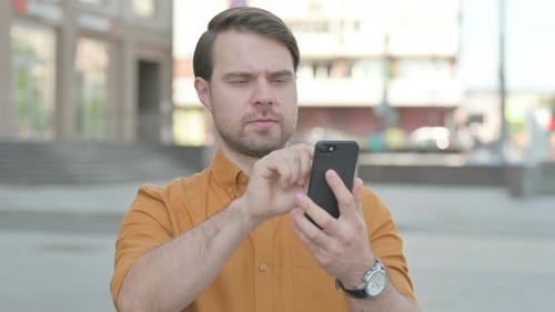 Man Using Smartphone in Urban Environment During Daytime