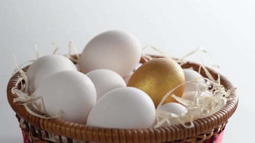 Close-up of a basket with white and golden chicken eggs.