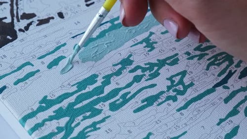 Person Painting a Canvas Using Paint-By-Numbers Kit