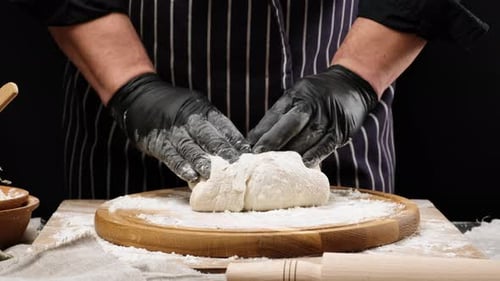 Baker Kneading Dough on a Wooden Board