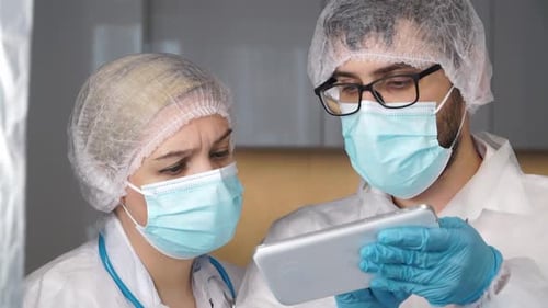 Medical Workers Viewing Digital Tablet in Protective Gear