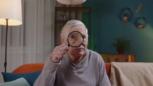 Senior Man Looking Through Magnifying Glass At Home