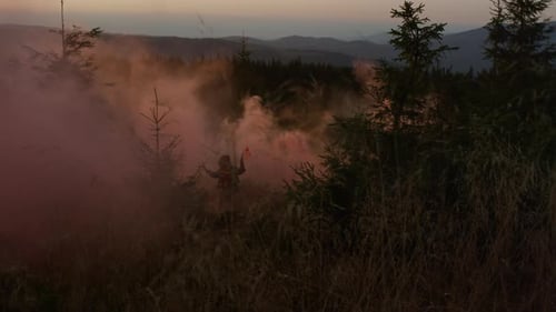 Person in Pink Smoke in Mountain Forest at Sunrise