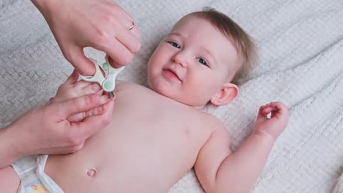 Infant Having Fingernails Clipped Indoors on Blanket
