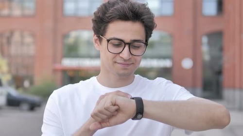 Young Man Checks Smart Watch in the City