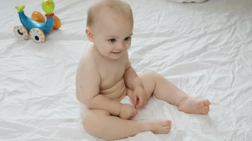 Happy Blond Infant Smiling and Playing on Blanket