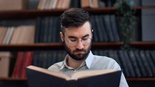 Fokussierter Geschäftsmann liest Vintage-Papierbuch in der Bibliothek Suche nach Informationen zu Bildungsdaten