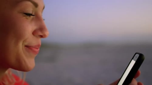 Woman using mobile phone on beach at dusk 4k