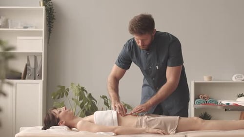 Man Performing Abdominal Massage on Woman Indoors