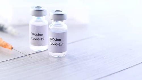 Nahaufnahme des Coronavirus-Impfstoffs und der Spritze auf weißem Hintergrund