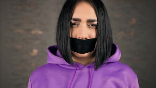 Sad Crying Young Woman Showing Emotions with Her Mouth Covered in Duct Tape