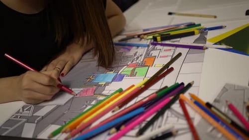 Woman Coloring Architectural Drawing at Table with Pencils