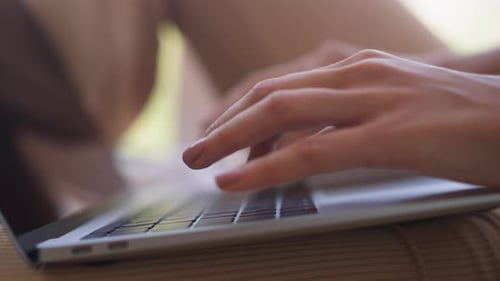 Young Woman Types Letter on Keyboard of Modern Laptop