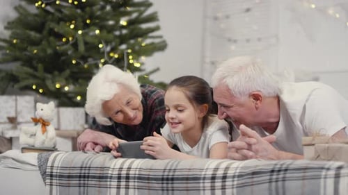 Grandparents and Grandchild Using Smartphone at Christmas