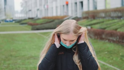 Young Woman Puts on Face Mask Outdoors
