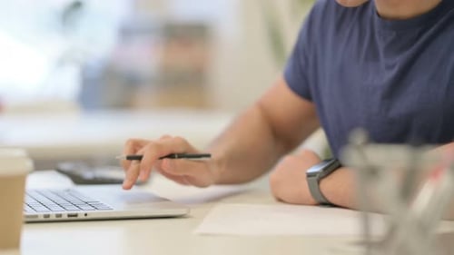 Close Up of Male Hands Writing on Paper While Using Laptop