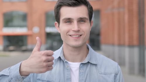 Young Man Gives Thumbs Up in Urban Setting