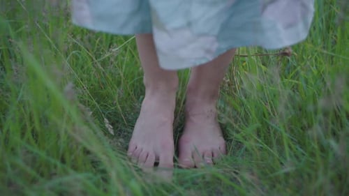 Pernas brancas femininas descalças em pé na grama verde no prado de verão. Pés de close-up de