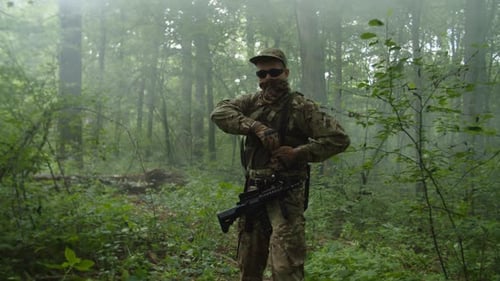 Un militaire observant la position ennemie lançant une grenade à main dans la forêt