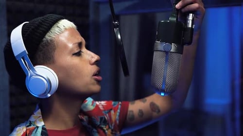 Young professional female singer recording a new song album inside music production studio