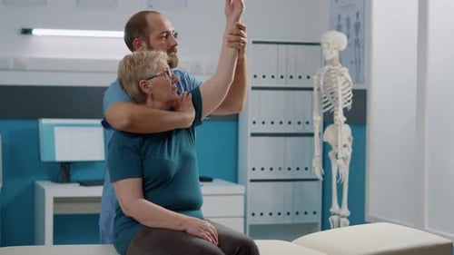 Physical Therapist Assists Senior Woman With Arm Raises