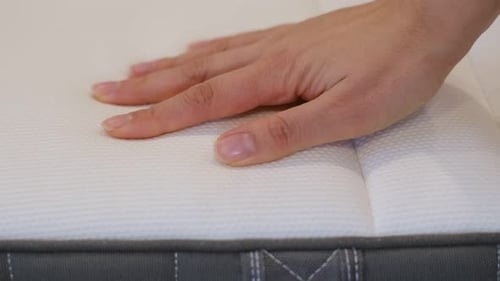 Hand Presses Down on Comfortable White Mattress