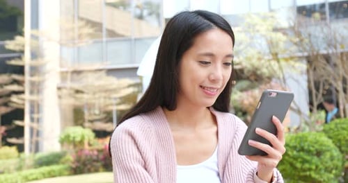 Smiling Woman Using Smartphone in Urban Setting