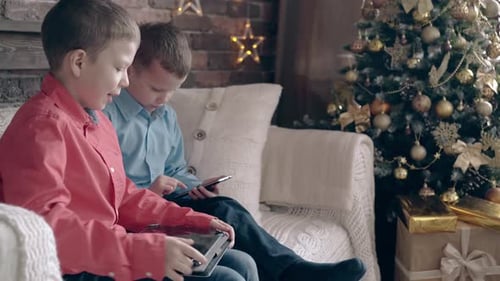Boys Using Tablets by Christmas Tree Indoors