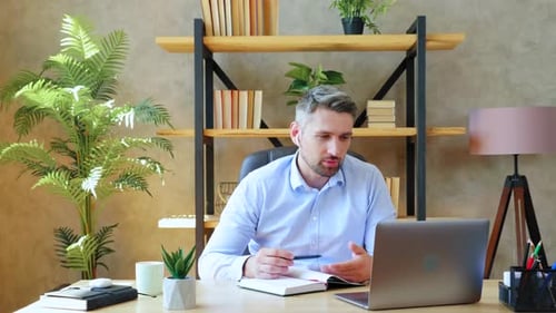 Man in home office wears wireless earphones study remote online video conference call with tutor