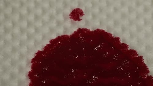 Red Liquid Spreads on Textured White Surface