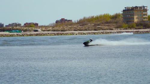 Ein Jetski fährt vor einem Deich über das Meer