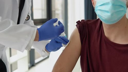 Medical Professional Giving Injection to Young Adult