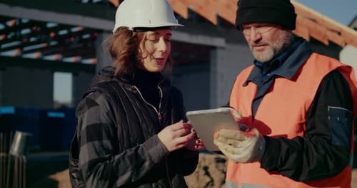 Construction Workers Reviewing Plans on a Tablet at Site