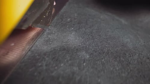 Person Cuts Black Leather Material with Knife on Table