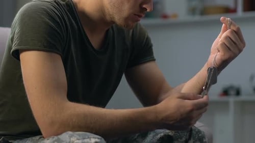 Man Holding and Fiddling with Dog Tags Indoors