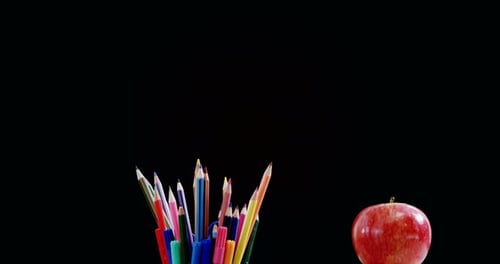 Apple on book stack with school supplies