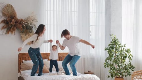 Happy Family Jumping on Bed in Bright Room