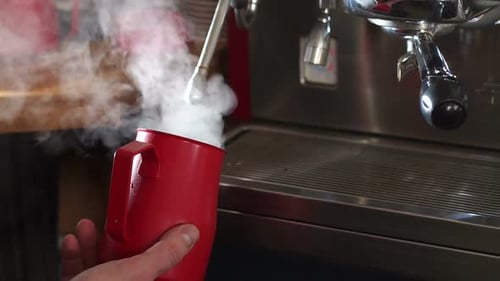 Close-up of a Male Barista Steaming a Cup of Milk Before Work.