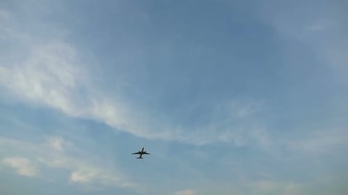 Airplane Flying Through The Blue Cloudy Sky