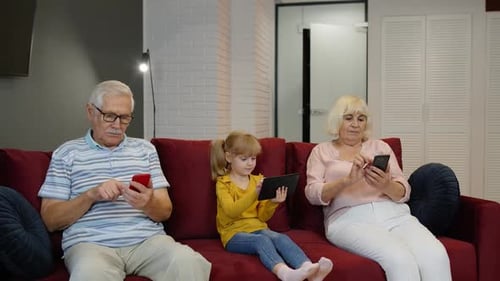 Family Together Using Technology on Red Couch