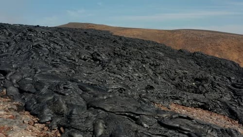 Slide and Pan Footage of Dark Stiffed Lava Stream on Rocky Ground