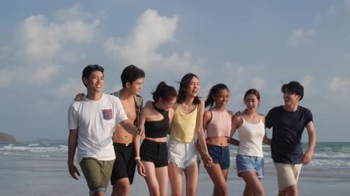 Young Adults Walking on Beach with Arms Around Each Other