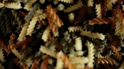 Rotini Pasta Macaroni vole après avoir explosé. Tas de pâtes multicolores Bouncing Black Bg