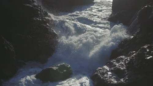 Slow motion close up shot of an ocean wave smashing on rocks and splashing